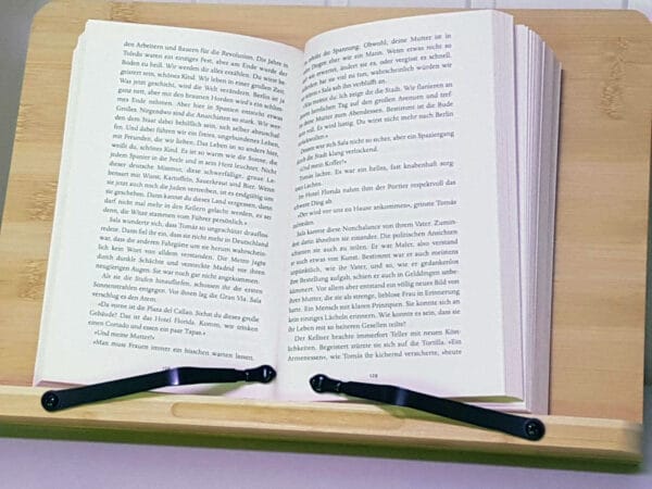 Hölzerner Buchständer mit zwei schwarzen Metallseitenhaltern und einem aufgeschlagenem Buch.