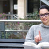 OrCam junge Frau auf Parkbank liest Buch